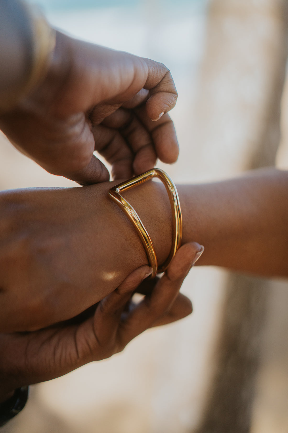 womans hands fastening a gold bracelet onto her wrist